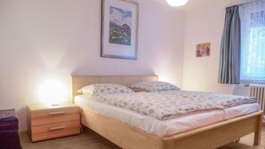 Ein Schlafzimmer mit einem hölzernen Bett, einem Nachttisch, einer Kommode und einem gerahmten Bild an der Wand.