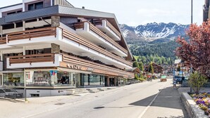 Un hôtel à plusieurs étages doté de balcons, une station de ski en arrière-plan et une vue sur les montagnes.