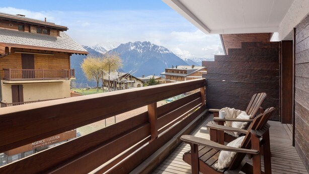 Une terrasse en bois avec une rambarde en bois, une chaise en bois et une table.