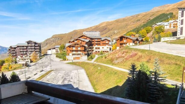A mountain resort with wooden buildings, a winding road, and a clear view of the surrounding hills.