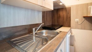 A modern kitchen with a stainless steel sink, wooden cabinets, and a built-in stove.