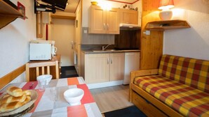 A compact kitchenette with a microwave, a small table with a basket of bread, and a sofa.