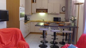 Una cocina compacta con una isla central, taburetes de bar y una mesa de comedor.