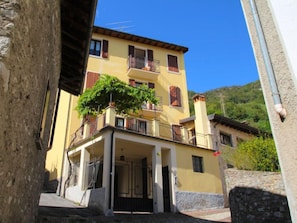 A two-story building with a balcony and a tree in front.