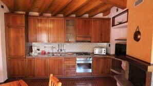 Una cocina con armarios de madera, estufa a gas, microondas y horno empotrado.