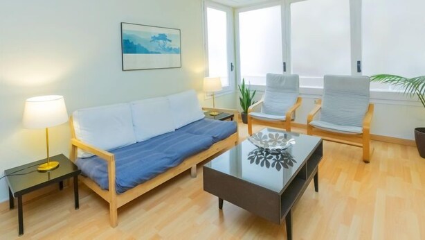 A modern living room with a sofa, two armchairs, a coffee table, and a painting on the wall.