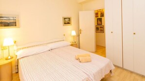 A bedroom with a bed, two bedside lamps, a door, and a wardrobe.