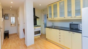 A kitchen with light-colored cabinets, a black countertop, and a microwave.