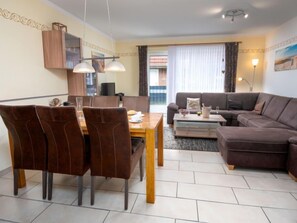 Een moderne woonkamer met een eethoek, een bank en een televisie.