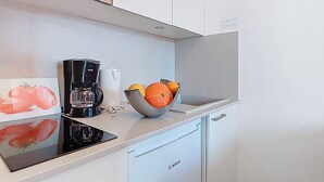 Ett kök med en kaffemaskin från Bosch, en skål med apelsiner och ett vitt skåp.