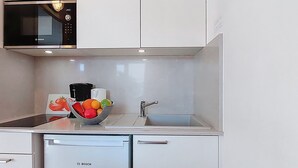 Ett kök med en Bosch-mikrovågsugn, en diskho och en diskmaskin.