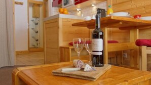 Une table en bois avec une bouteille de vin, deux verres et quelques amuse-gueules.