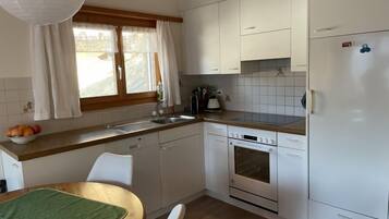 Une cuisine compacte avec des meubles blancs, un four encastré et un lave-vaisselle.
