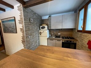Een kleine keuken met een houten aanrecht, een ingebouwde kookplaat en een koelkast.