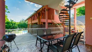 Un espacio al aire libre cubierto con una mesa, sillas, una parrilla y una escalera en espiral.