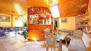 Una sala de estar acogedora con techo de madera, una zona de bar con botellas y un sofá.
