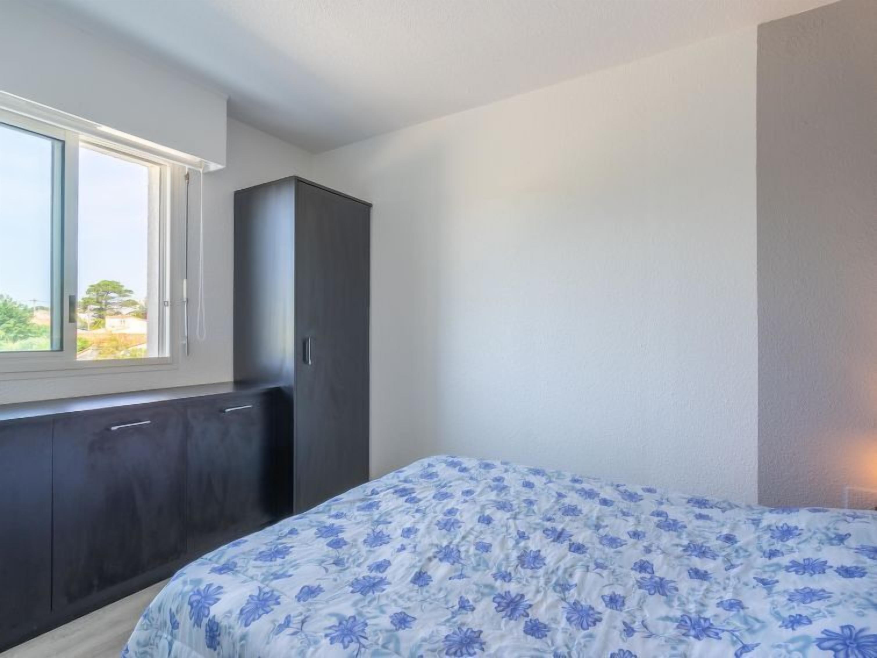 A bedroom with a bed, a wardrobe, and a window.