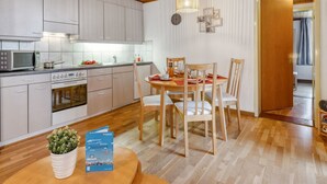 Een moderne keuken met witte kastjes, een magnetron, en een eethoek met een houten tafel en stoelen.