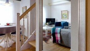 Ein modernes Wohnzimmer mit Treppe, Essbereich und Fernseher.