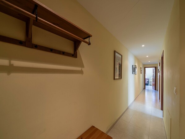 Un pasillo con un banco de madera, un estante en la pared y cuadros enmarcados.