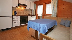 A compact kitchen with white cabinets, a stove, and a table with a blue tablecloth.
