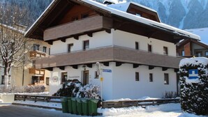 A two-story building with a sloped roof, a sign reading "Sonnenheim," and a view of snow-covered mountains.