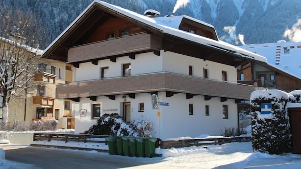 A two-story building with a sloped roof, likely a hotel, surrounded by snow-covered mountains.