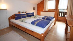 A wooden-framed bed with blue and white bedding, a small bedside table, and a window with curtains.