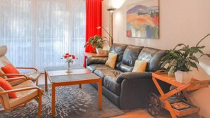Un salon moderne avec un canapé en cuir, deux fauteuils, une table basse et un rideau rouge.