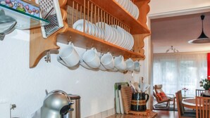 Une cuisine équipée d’une machine à café, d’une bouilloire et d’une cafetière sur le plan de travail. Des étagères situées au-dessus servent à ranger les assiettes et les tasses.