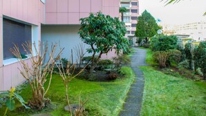 Un chemin menant à un bâtiment à la façade rose, entouré de verdure et de petits arbres.