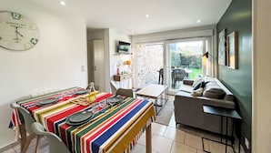 A dining area with a striped tablecloth, a clock, and a television on the wall. - Les Alizés by Interhome (Carnac)