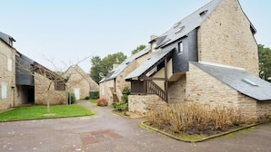 A stone building with a sloped roof, a small garden area, and a paved walkway. - Les Alizés by Interhome (Carnac)
