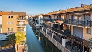 A canal-side residential area with multi-story buildings, balconies, and a clear sky. - La Perouse D1/2 by Interhome (Le Bouveret)