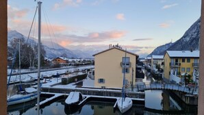 A marina with boats docked, a small building with a flat roof, and mountains in the background. - La Perouse D1/2 by Interhome (Le Bouveret)