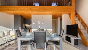 A modern dining area with a glass table and chairs, a television, and a staircase. - La Perouse D1/2 by Interhome (Le Bouveret)