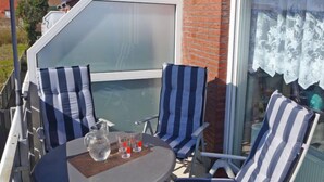 A patio with a round table, striped chairs, a pitcher of water, and two glasses. - Am Koper Sand by Interhome (Norddeich)