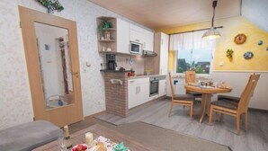 A compact living space with a kitchenette, dining area, and a small seating area with a table and chairs. - Am Koper Sand by Interhome (Norddeich)