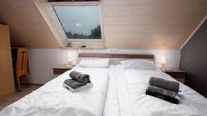A bedroom with a skylight, two beds, bedside lamps, and a nightstand. - Am Koper Sand by Interhome (Norddeich)