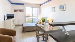 Habitació compacta amb llit, taula de menjador, televisió i un balcó amb vistes.