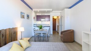 Habitació d'hotel moderna amb llit, escriptori i petita cuina.