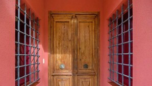 Une porte à deux battants en bois, renforcée par des barreaux métalliques, située dans un couloir aux murs rouges.