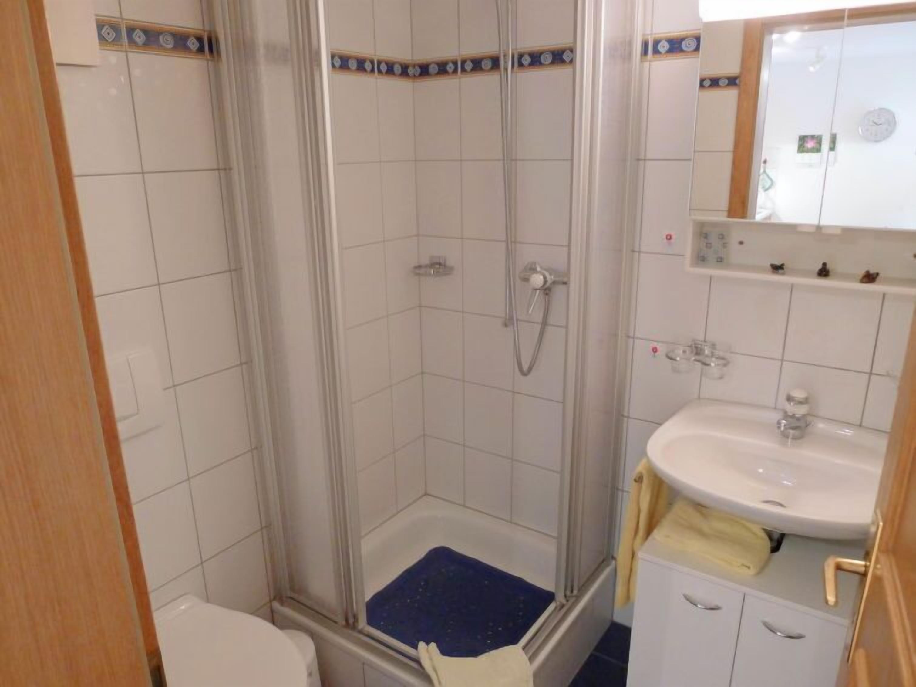 Et badeværelse med bruser, toilet og vask.