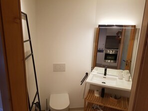 Een kleine badkamer met een wit wastafel, spiegel en toilet.
