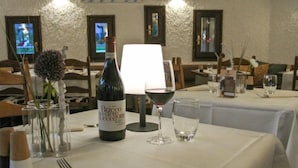 Ein Esstisch, gedeckt mit einer Flasche Brico del'Occellone Wein, einem Weinglas, einem Wasserglas und Besteck.