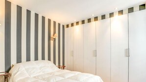 Ein Schlafzimmer mit Bett, Nachttisch, Kleiderschrank und einer Wandleuchte.