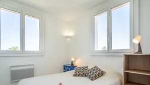 A bedroom with a bed, two bedside lamps, a nightstand, a radiator, and a wooden shelf. - La Sirene by Interhome (Saint Cyr sur mer Les Lecques)