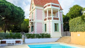 Ein mehrstöckiges Gebäude mit Pool, umgeben von Grünflächen und einem weißen Zaun.