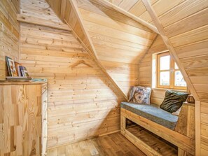 Un dormitorio acogedor en el ático, con paredes de madera y techo inclinado.