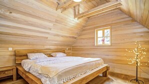 A cozy wooden room with a bed, a small window, and a decorative light fixture. - Plitvice I by Interhome (Plitvice)